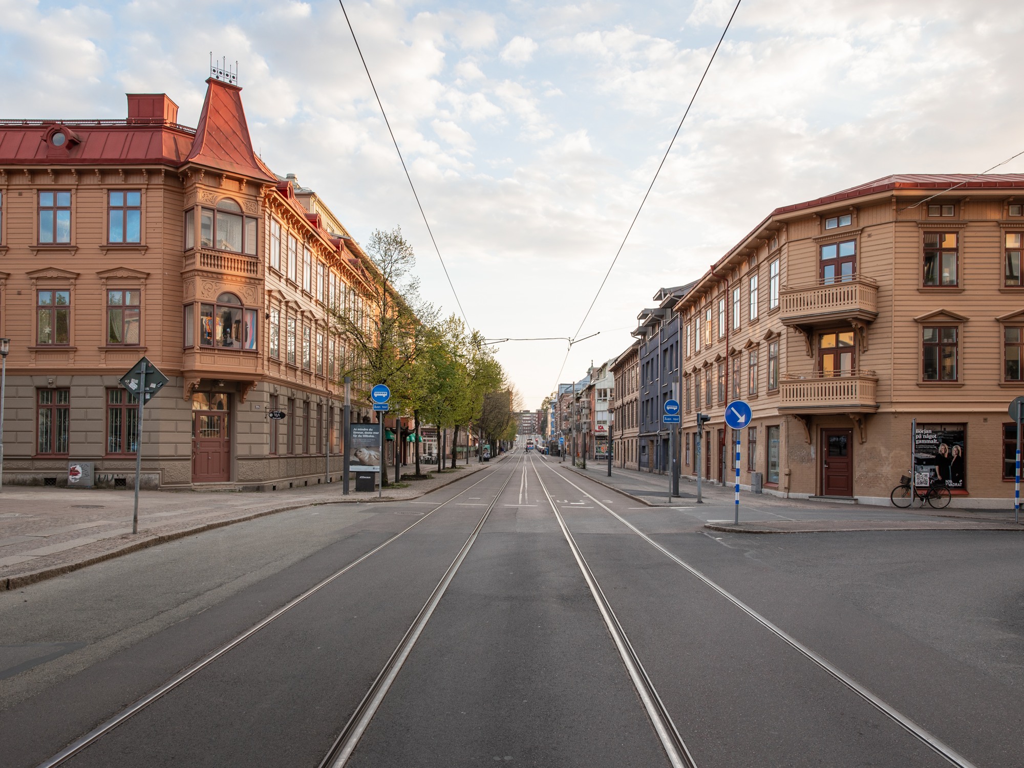 View of a street with tram tracks in the middle and orange buildings on each side of the street.