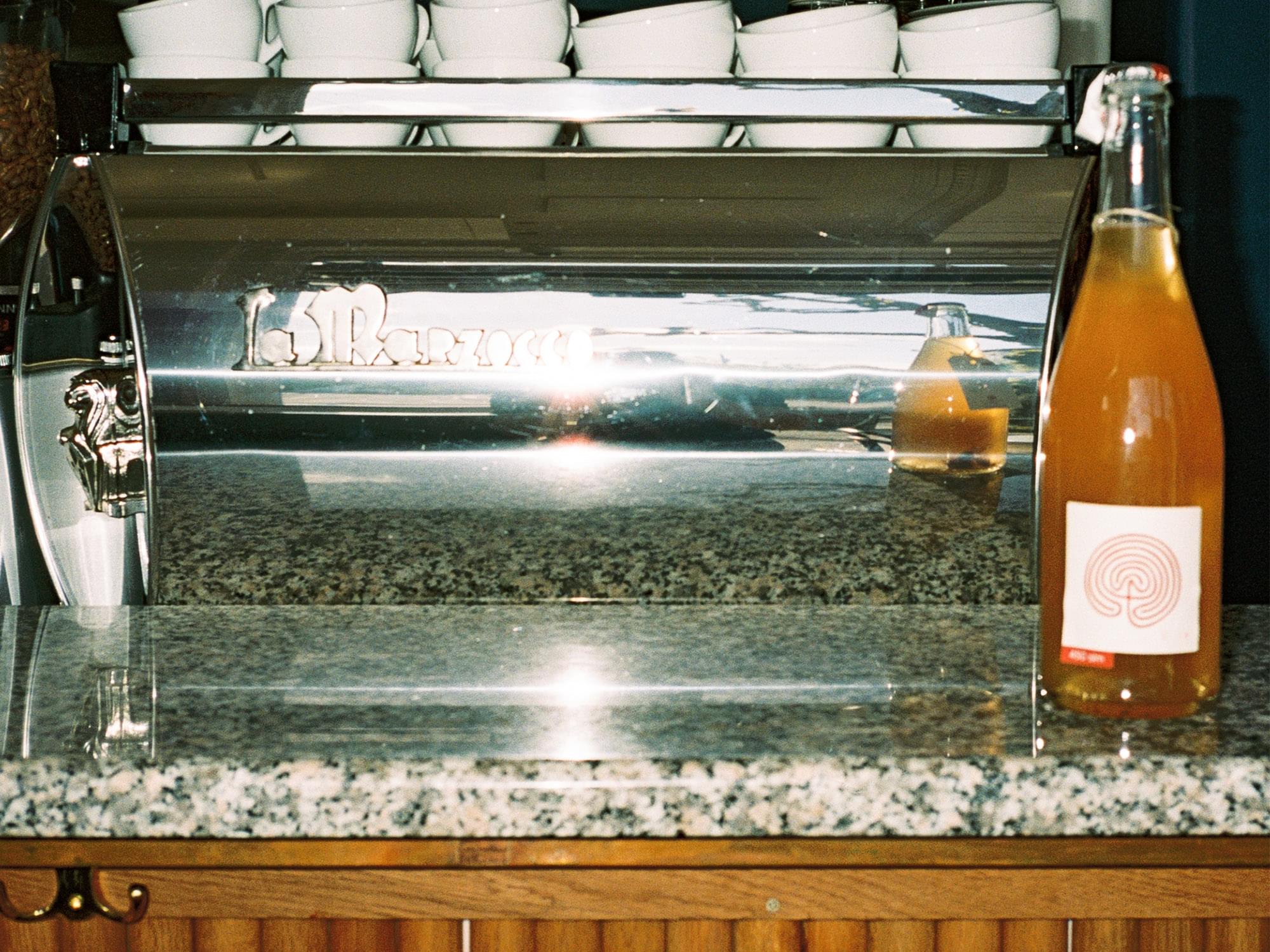 Vinflaska står på bänkskiva framför kaffemaskin.