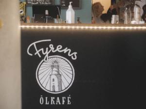 Black counter with a white logo saying "Fyrens Ölkafé" with a strip light above.