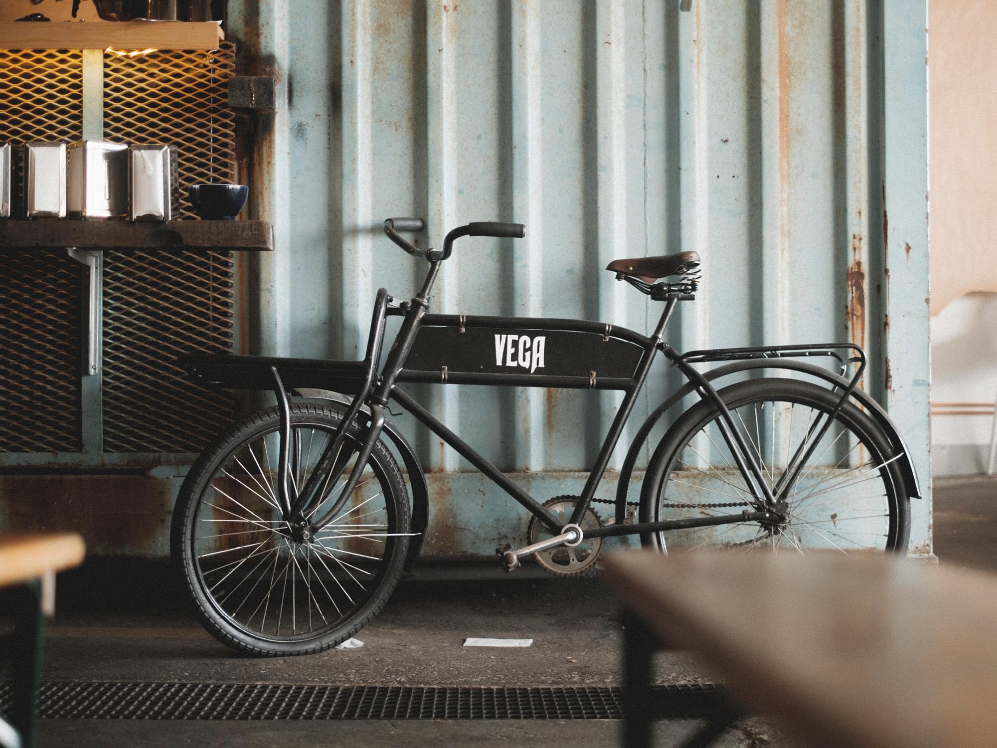 En svart cykel med texten Vega står mot en container.