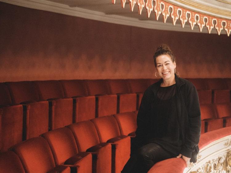 Kvinna sitter på kant på en av Stora Teaterns balkonger.