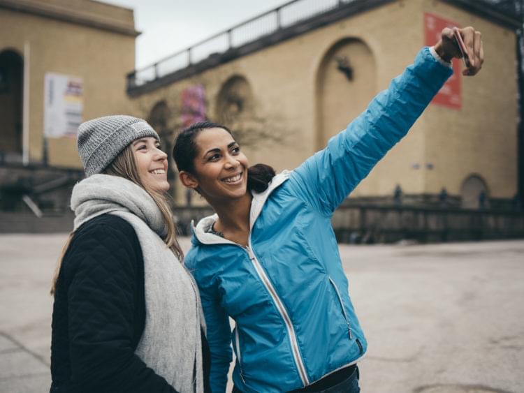 Två kvinnor tar en selfie vid Götaplatsen.