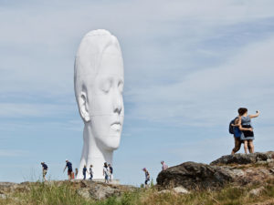 Skulptur i form av ett huvud i ett naturområde.