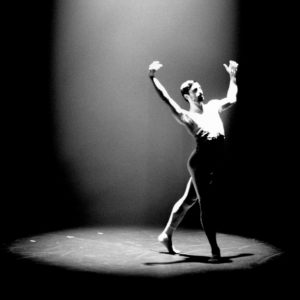 Person dansar på en scen, upplyst av en ensam ljuskägla.