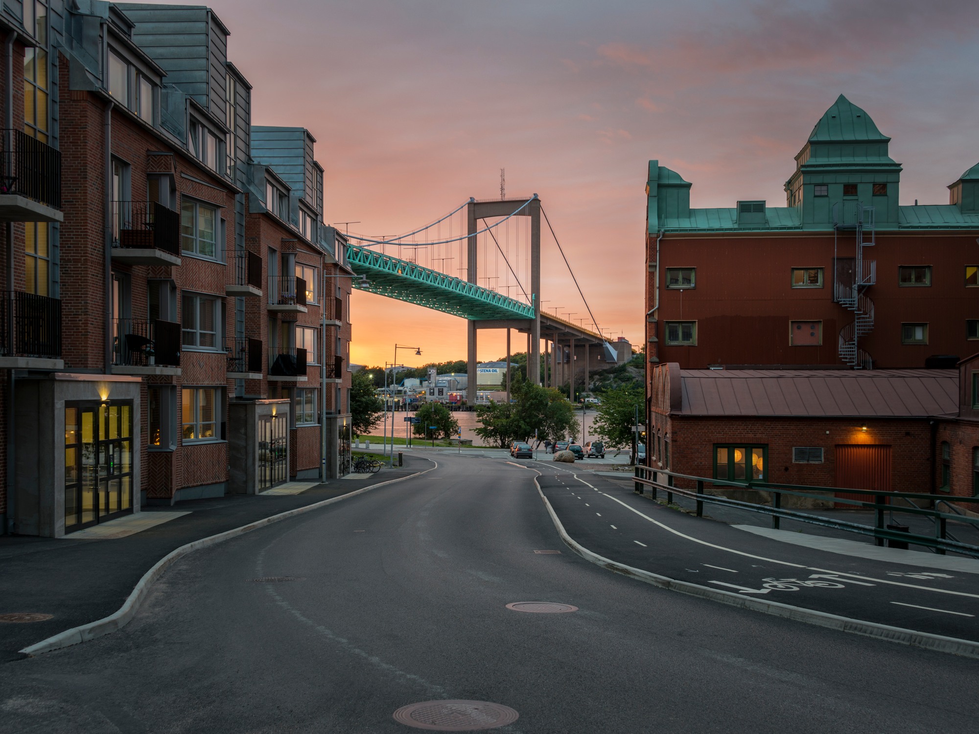 View of a sunset from a street overlooking a bridge.