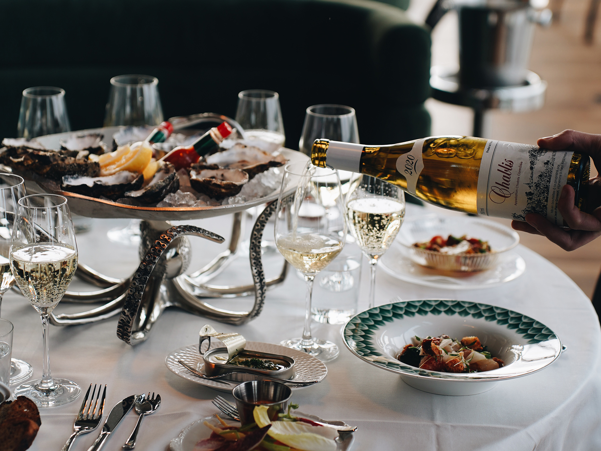 Vin hälls upp i glas på ett bord med skaldjursrätter. På restaurangen Brasserie Draken i Göteborg.