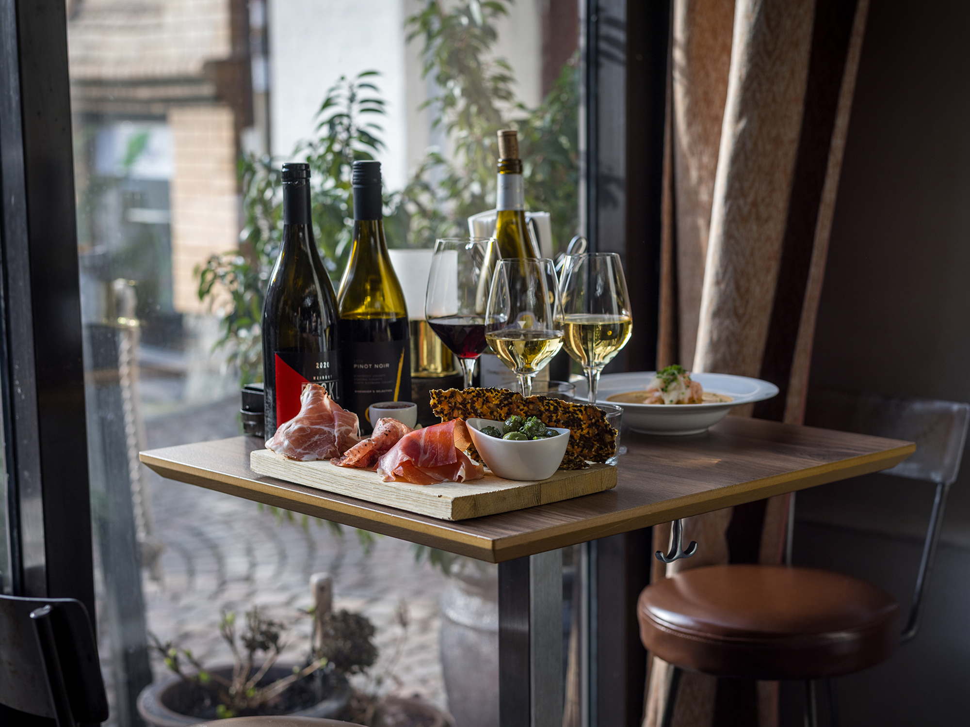 Dukat bord med rött och vitt vin och olika tapas som serrano och knäckebröd