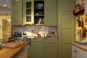 Kitchen decoration with green cabinets and different items in exhibition such as brushes, liquid hand soap, books, etc.